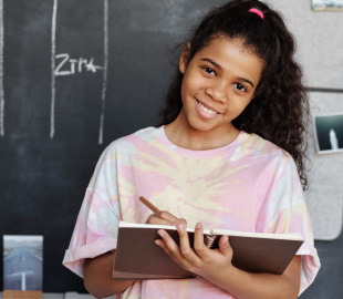 A smiling girl holding a notebook